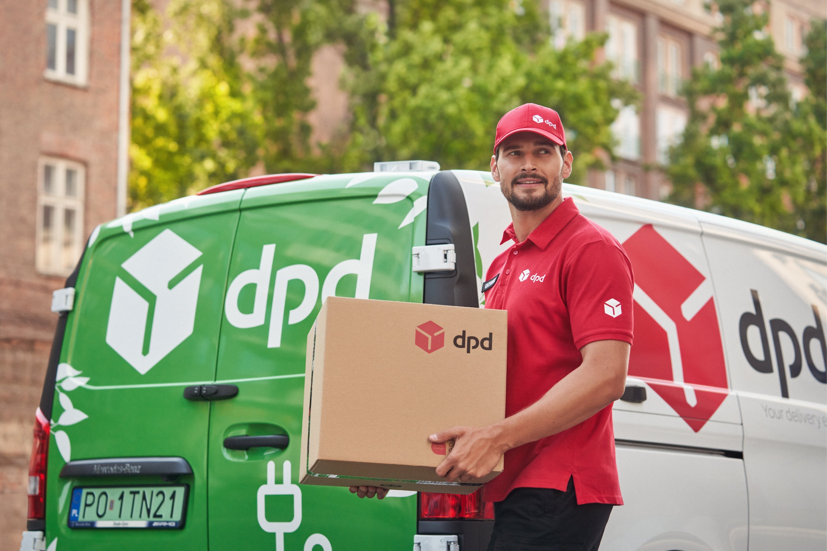 Kurier DPD z ekologiczną paczką stojący przy elektrycznym vanie dostawczym – zrównoważona logistyka DPD Food, wspierająca lokalnych producentów i redukująca ślad węglowy transportu na terenie miast.